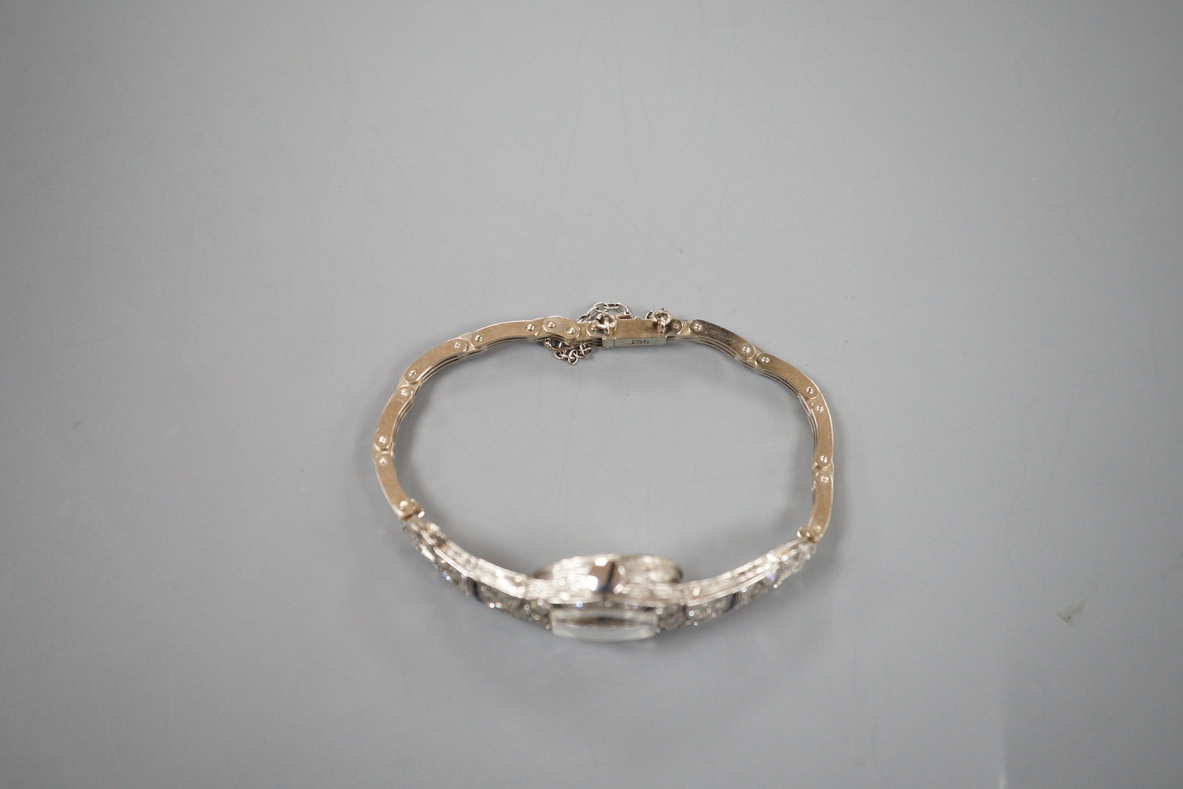 A lady's mid 20th century white metal, sapphire and diamond cluster set cocktail watch, on a 9ct bracelet (a.f.), gross weight 17.2 grams.